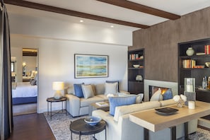 A modern living room with a sofa set, a coffee table, a side table with a lamp, a bookshelf, and a fireplace.