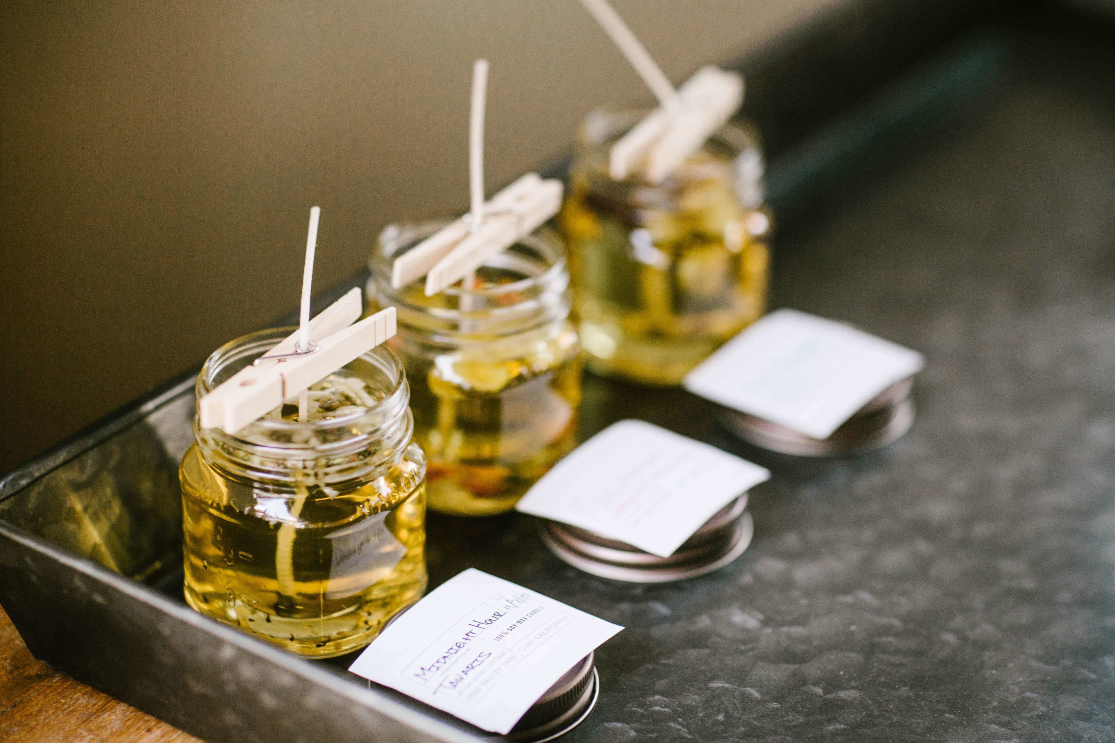 Three glass jars with straws on a metal tray, each with a white label.