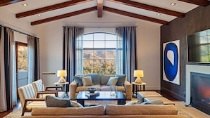 A spacious living room with a high ceiling, large windows, and a fireplace. - Ojai Valley Inn (Ojai)