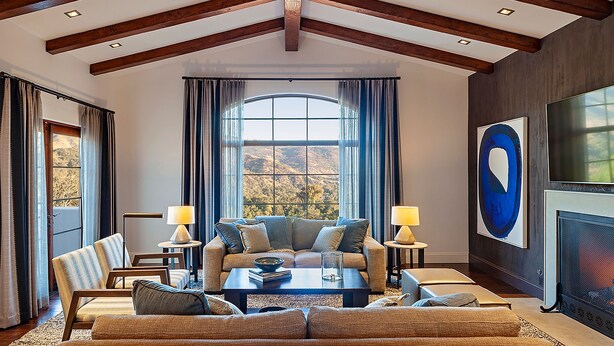 A spacious living room with a high ceiling, large windows, and a fireplace. - Ojai Valley Inn (Ojai)