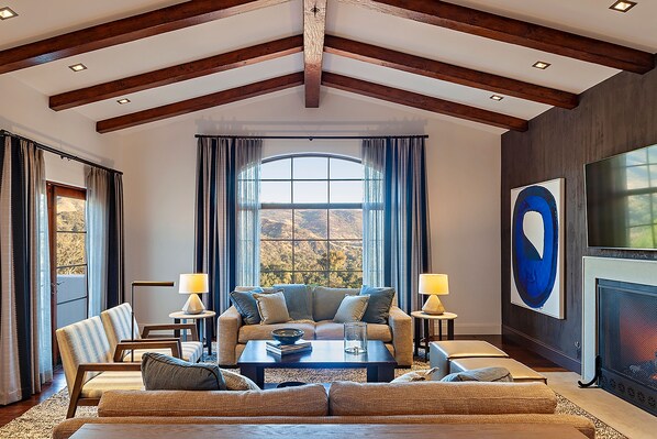 A spacious living room with a high ceiling, large windows, and a fireplace. - Ojai Valley Inn (Ojai)