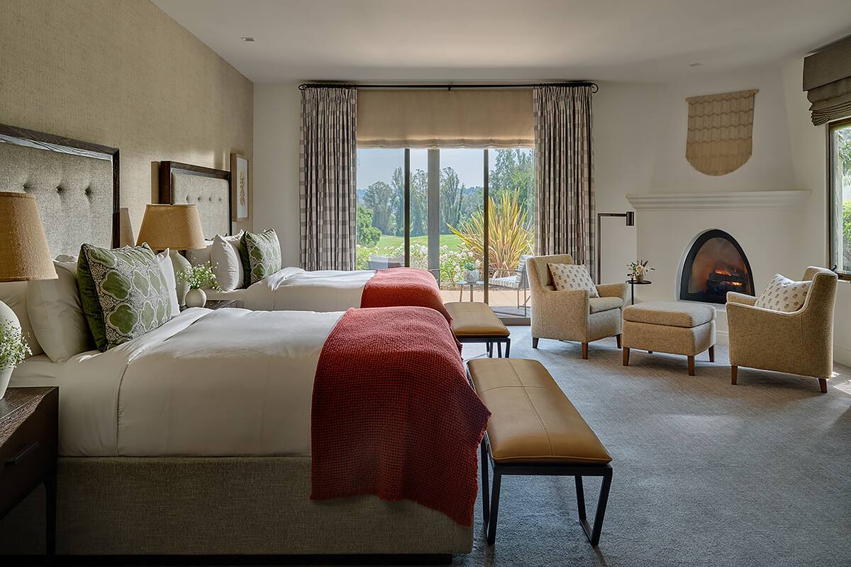 Une chambre d’hôtel avec deux lits, une cheminée, un canapé et une vue sur l’extérieur.