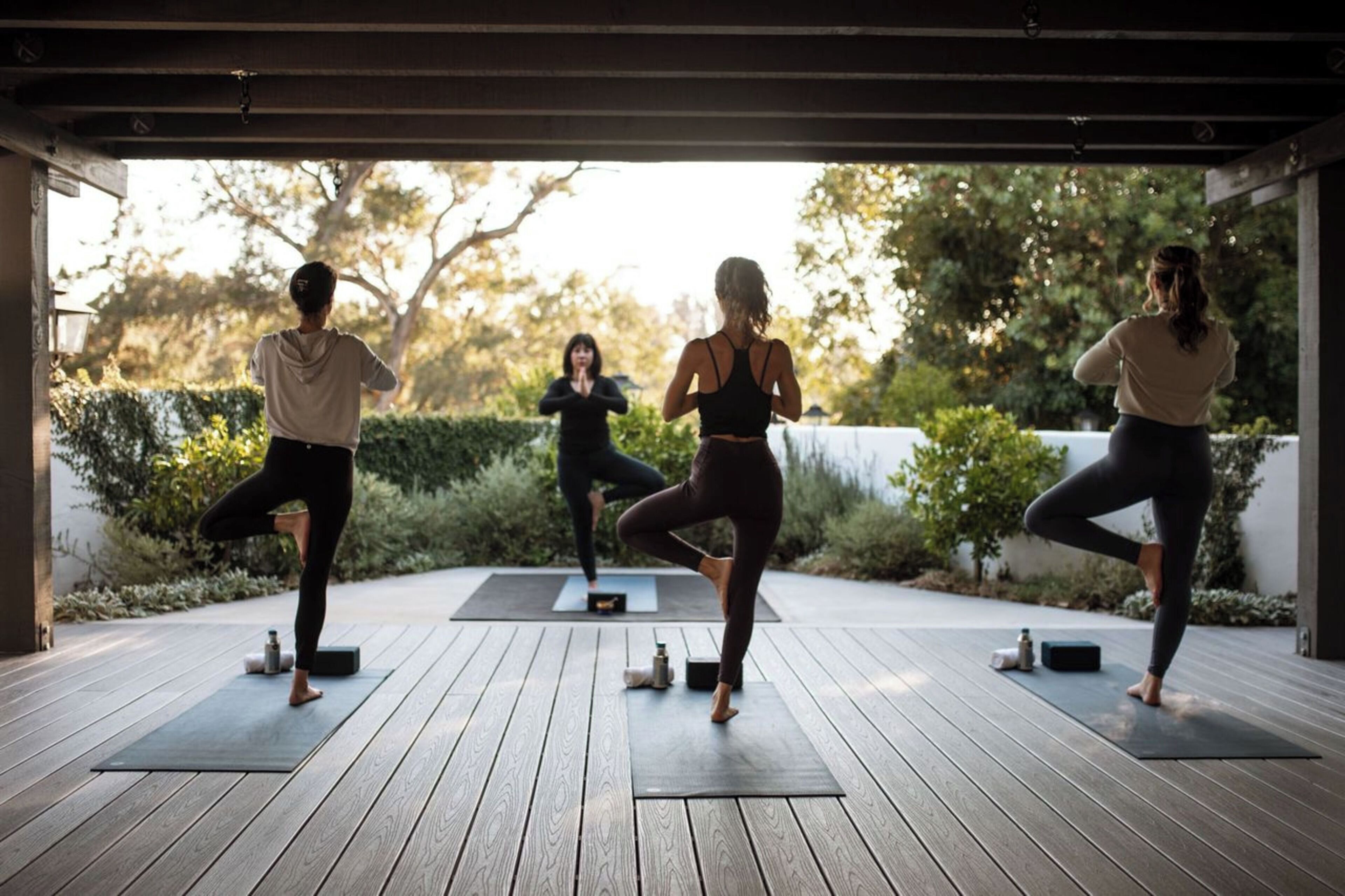 A group of people practicing yoga on outdoor wooden decks with exercise mats.
