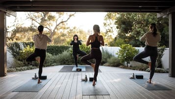 A group of people practicing yoga on outdoor wooden decks with exercise mats.