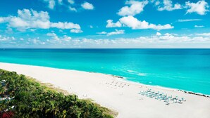 A beach with white sand, turquoise water, and a clear blue sky.