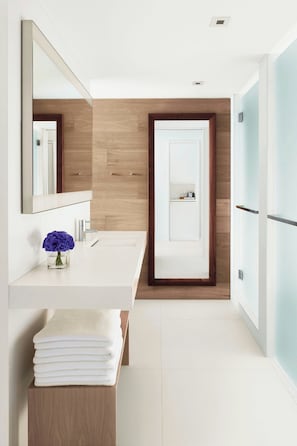 A modern bathroom with a white vanity, a mirror, and a wooden accent wall.