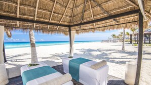 A beachside spa with two massage tables under a thatched roof, overlooking a sandy beach and ocean. - Sunscape Cancun All-Inclusive Resort & Spa by Hyatt (Cancun)