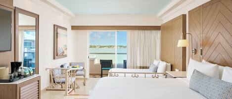 Habitación de hotel con una cama grande, un escritorio, una silla, un ventanal con cortinas y un ventilador de techo.