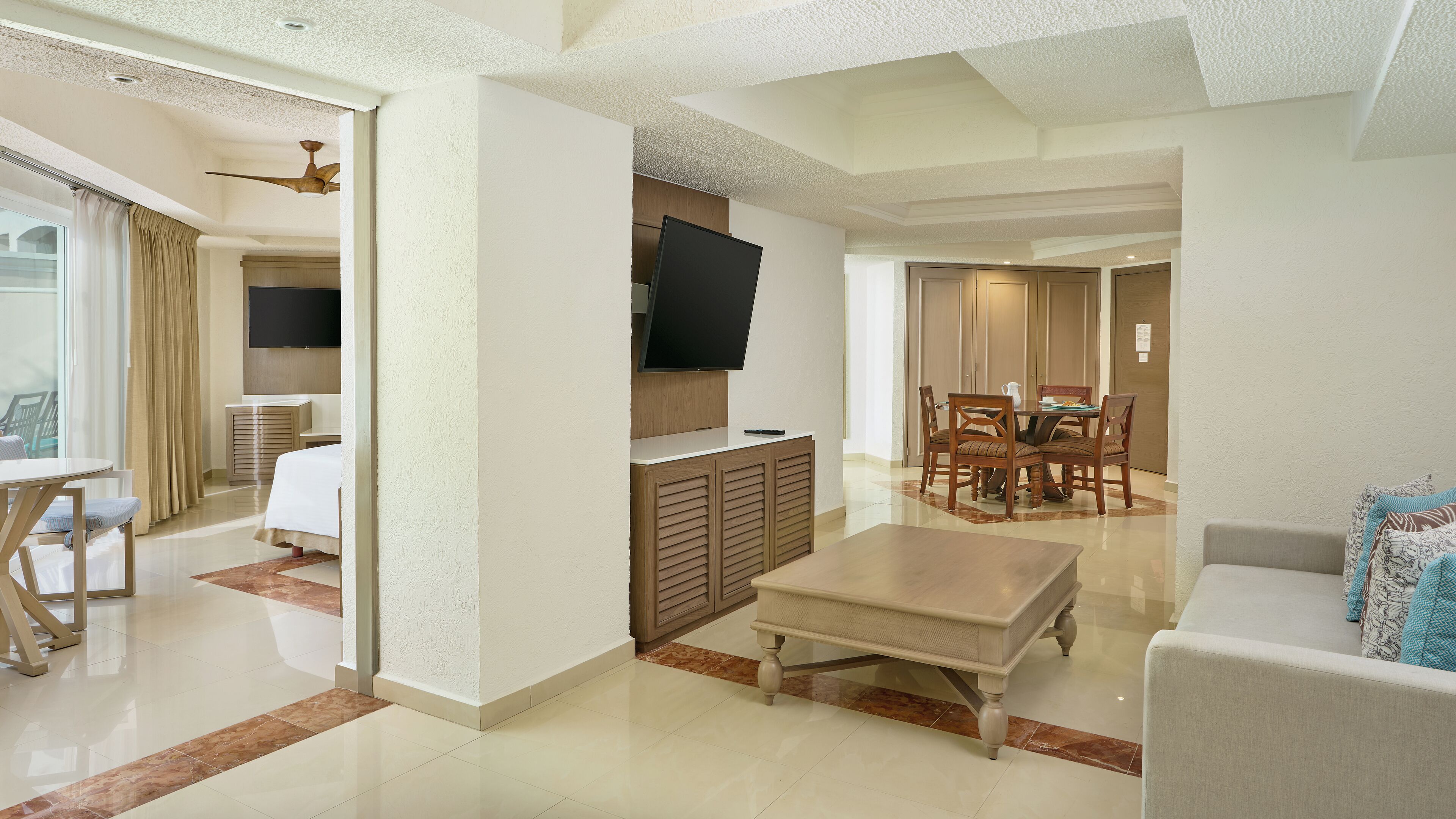 Una sala de estar moderna con un televisor de pantalla plana, una zona de comedor con mesa y sillas, y un sofá.