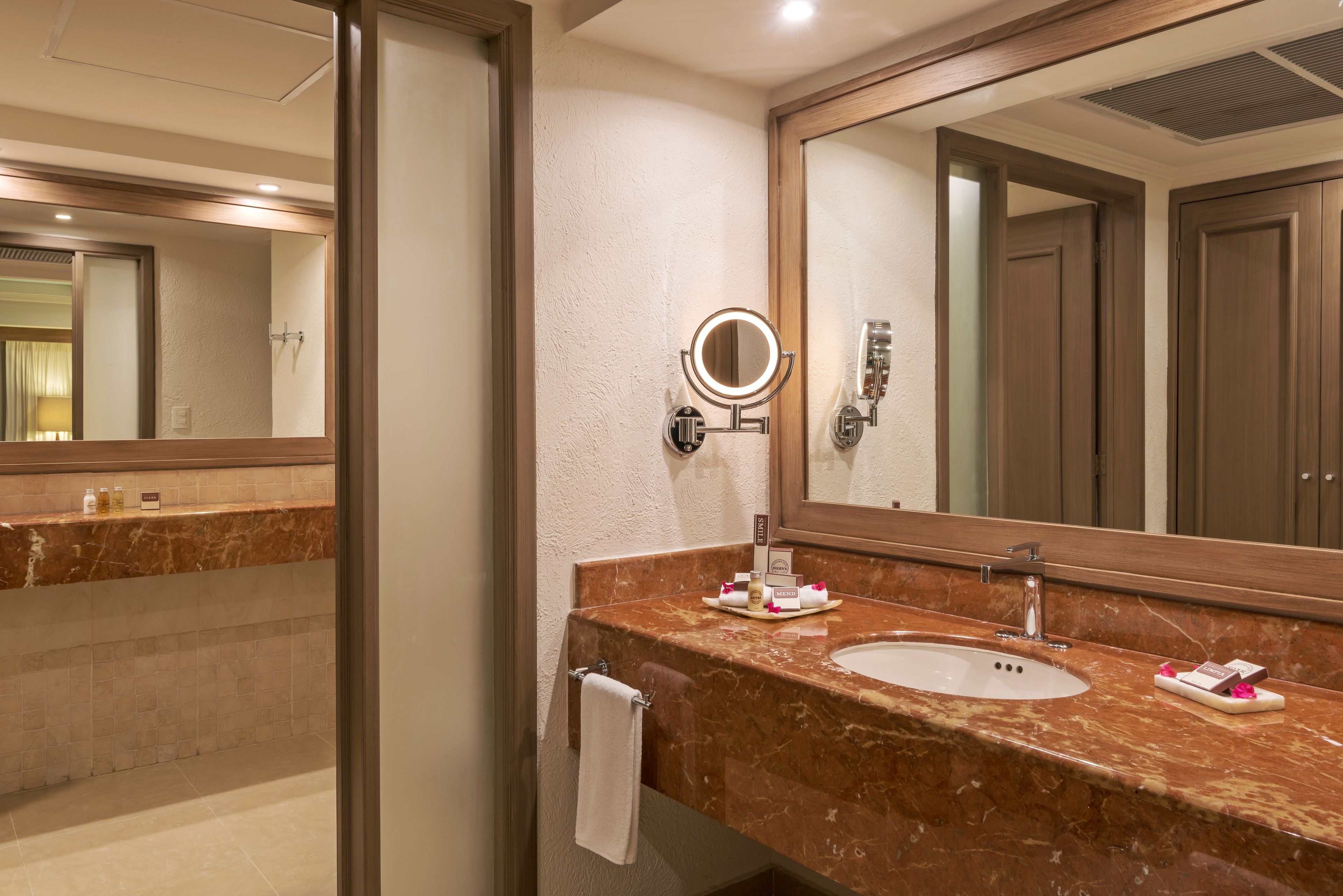 A bathroom with a marble sink, a large mirror, and a towel rack.