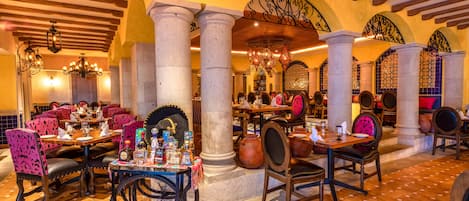 Un restaurante con varias mesas y sillas, una bicicleta y una variedad de botellas y vasos sobre las mesas.