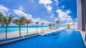 A pool area with a view of the beach and ocean, surrounded by palm trees and lounge chairs. - Sunscape Cancun All-Inclusive Resort & Spa by Hyatt (Cancun)