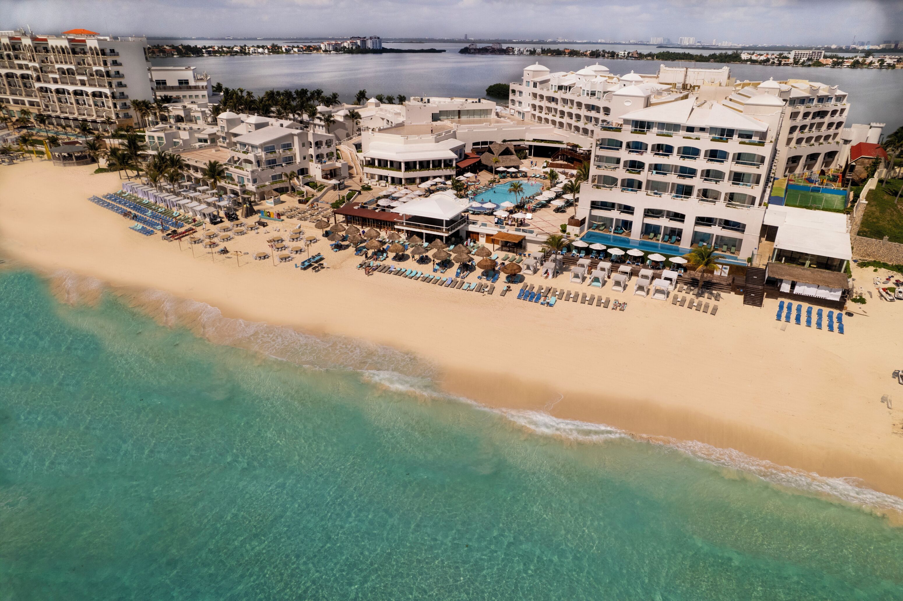 An aerial view of a resort with a beachfront, multiple buildings, and a pool area.