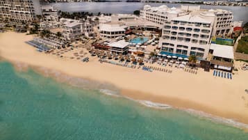 An aerial view of a resort with a beachfront, multiple buildings, and a pool area.