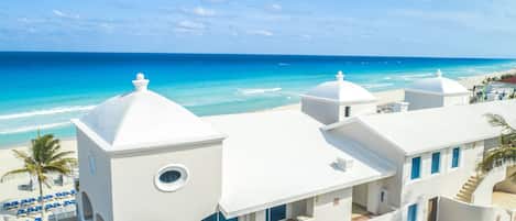 Un edificio blanco con vista a la playa, varios balcones y una zona de piscina.