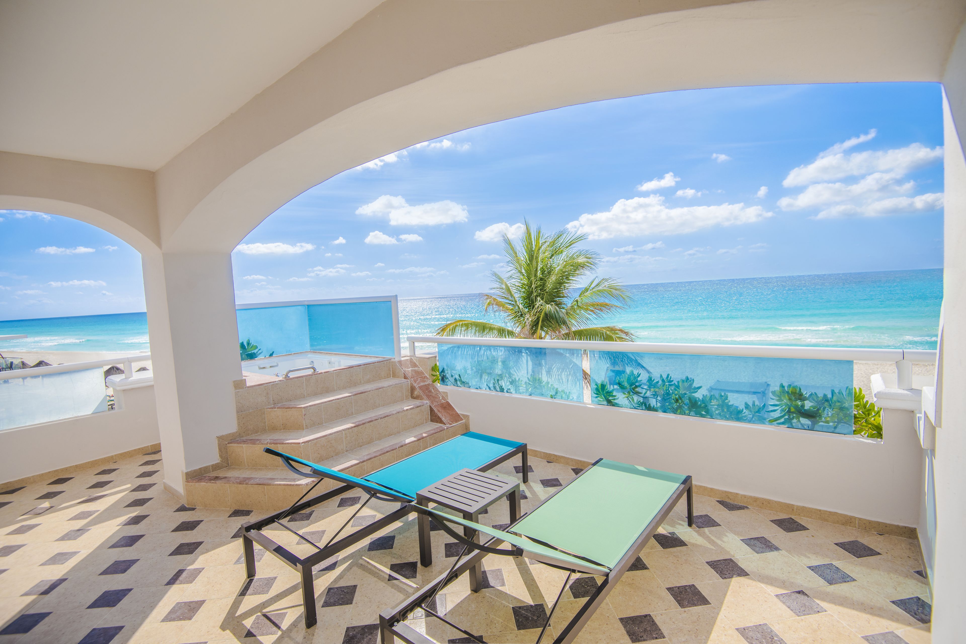 Een balkon met uitzicht op de oceaan, een palmboom en een betegelde vloer.