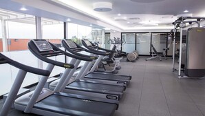 Un gimnasio con cintas de correr, máquinas de pesas y un amplio ventanal.