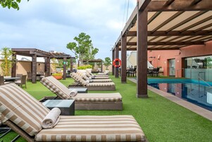 Una piscina al aire libre, sillones reclinables de piscina
