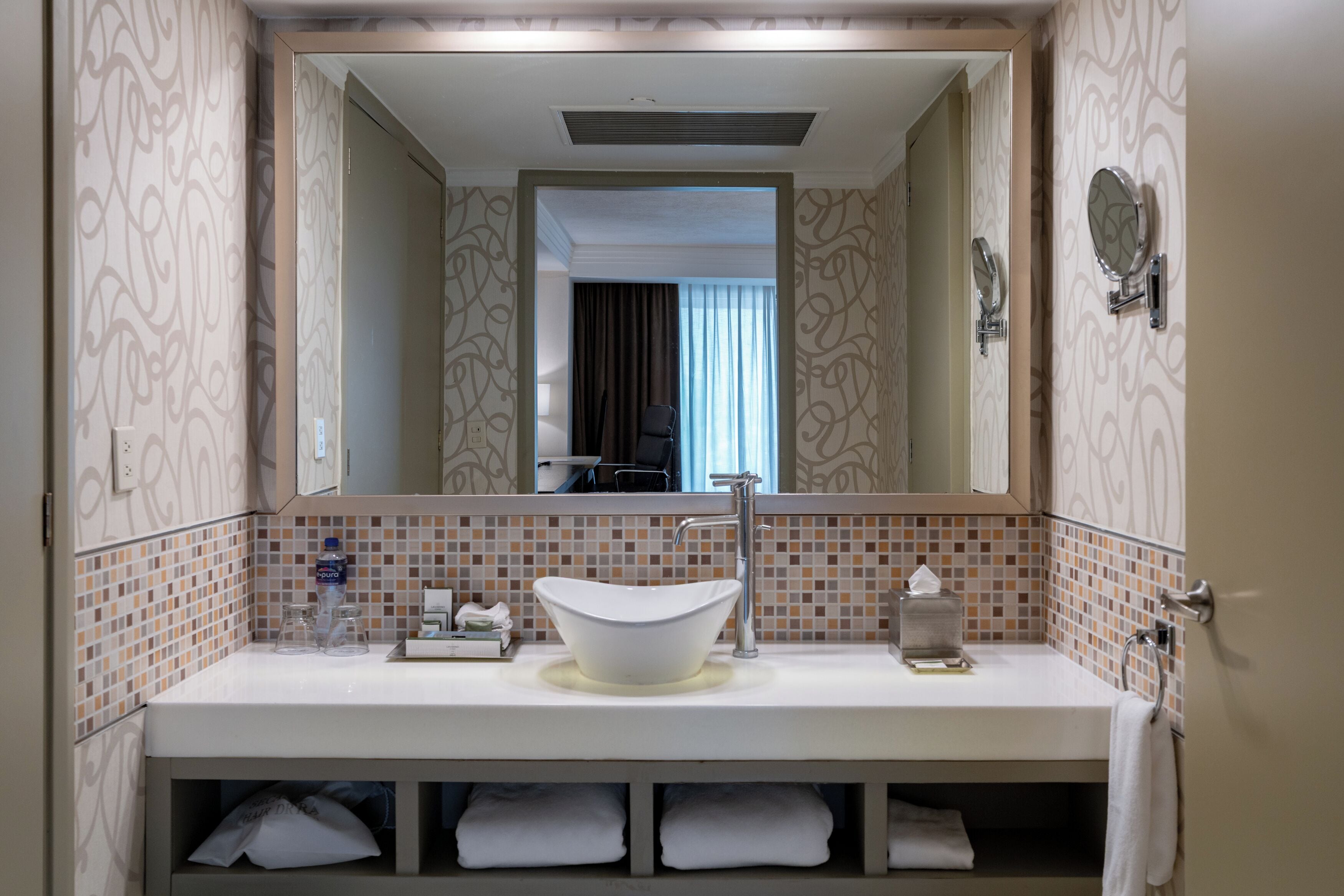 A bathroom with a white sink, a mirror, and a towel rack.
