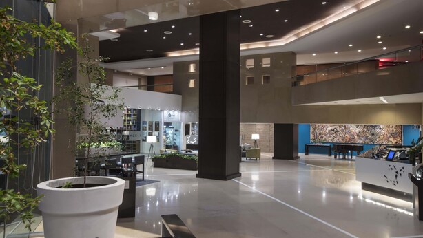 Un lobby amplio con una recepción, zonas de estar y un gran mural abstracto.