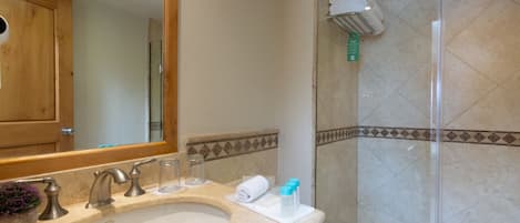 A bathroom with a sink, mirror, and shower area.
