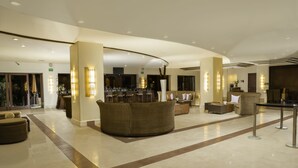 A spacious lobby with a curved ceiling, a reception desk, and comfortable seating areas. - Tesoro Los Cabos (Cabo San Lucas)
