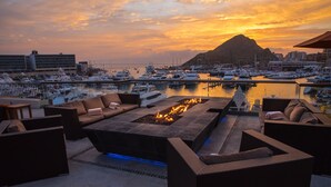 A rooftop terrace with a fire pit, outdoor seating, and a marina view at sunset. - Tesoro Los Cabos (Cabo San Lucas)