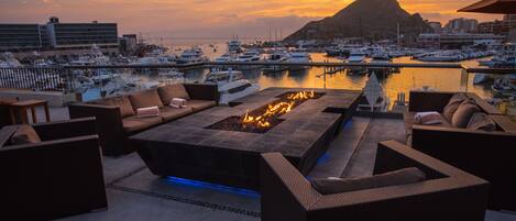 Terraza en la azotea con una chimenea, asientos exteriores y vistas al puerto al atardecer.
