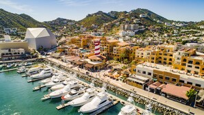 A coastal town with a marina, buildings with balconies, and a prominent lighthouse. - Tesoro Los Cabos (Cabo San Lucas)