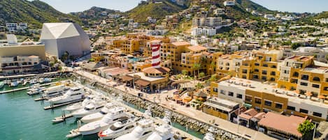 A coastal town with a marina, buildings with balconies, and a prominent lighthouse.
