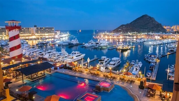 A marina with boats docked, a pool area with umbrellas, and a mountain in the background. - Tesoro Los Cabos (Cabo San Lucas)