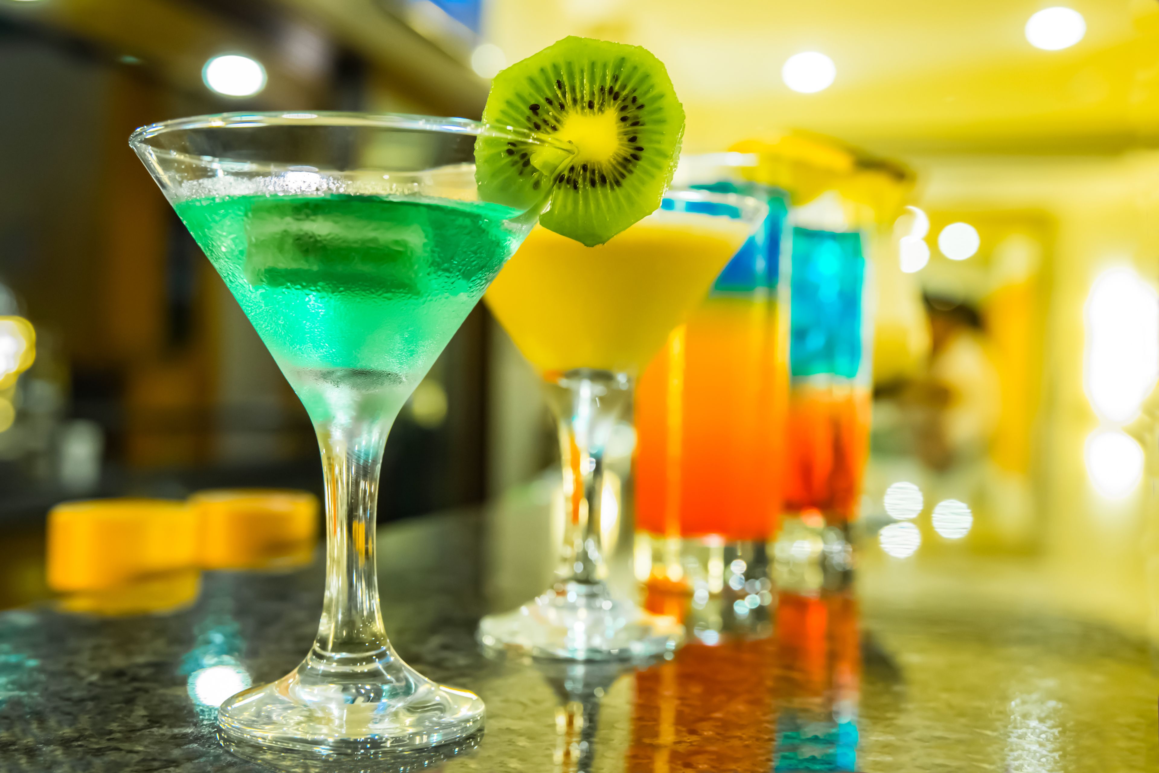 Un bar proposant une variété de cocktails colorés, chacun agrémenté d’une tranche de kiwi.