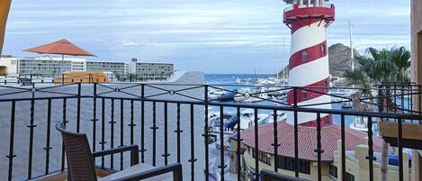 Ein Balkon mit Korbmöbeln, ein rotes und weißes Leuchtturm und ein Yachthafen im Hintergrund.
