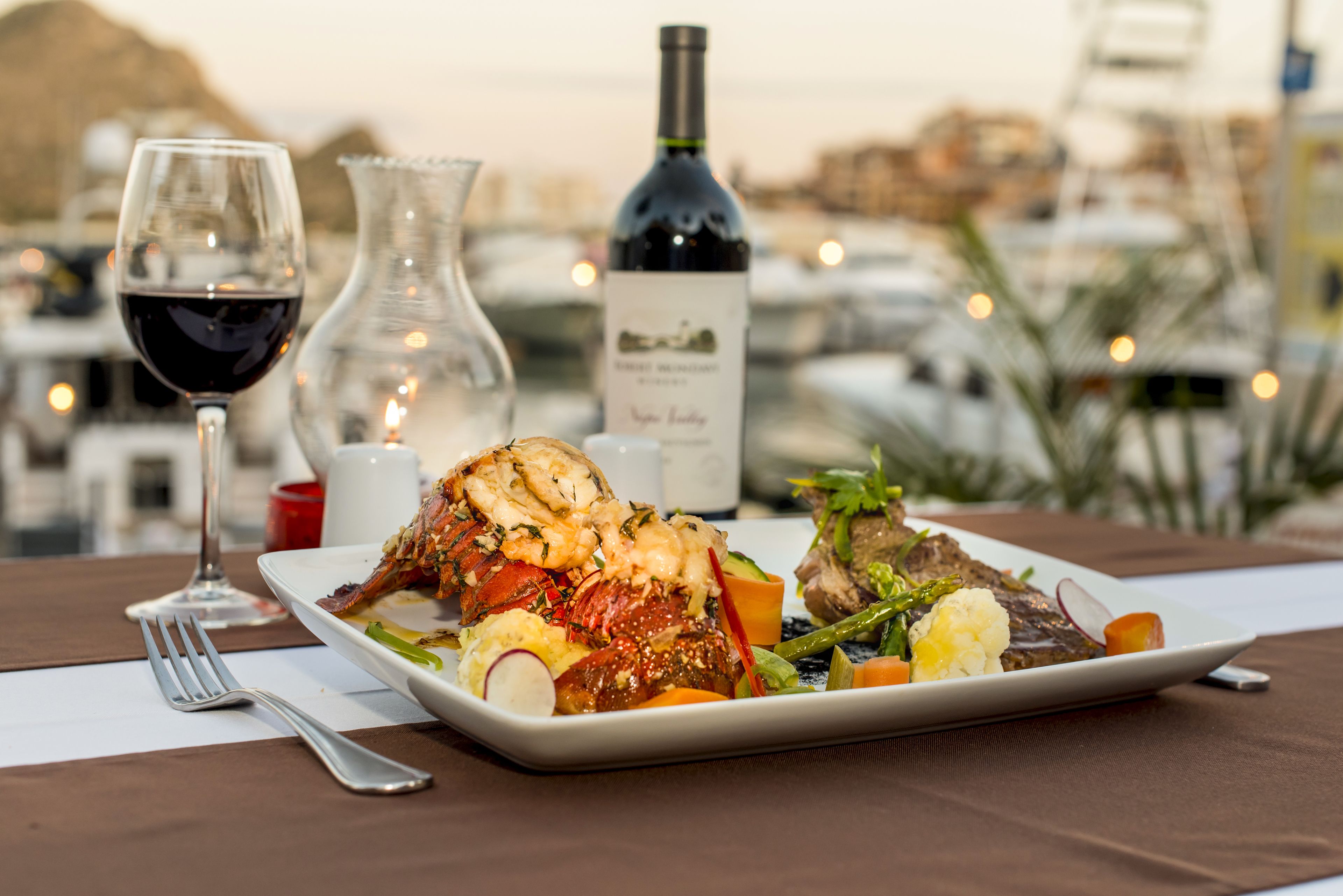 Une table à manger avec une assiette de nourriture, un verre à vin et une bouteille de vin.