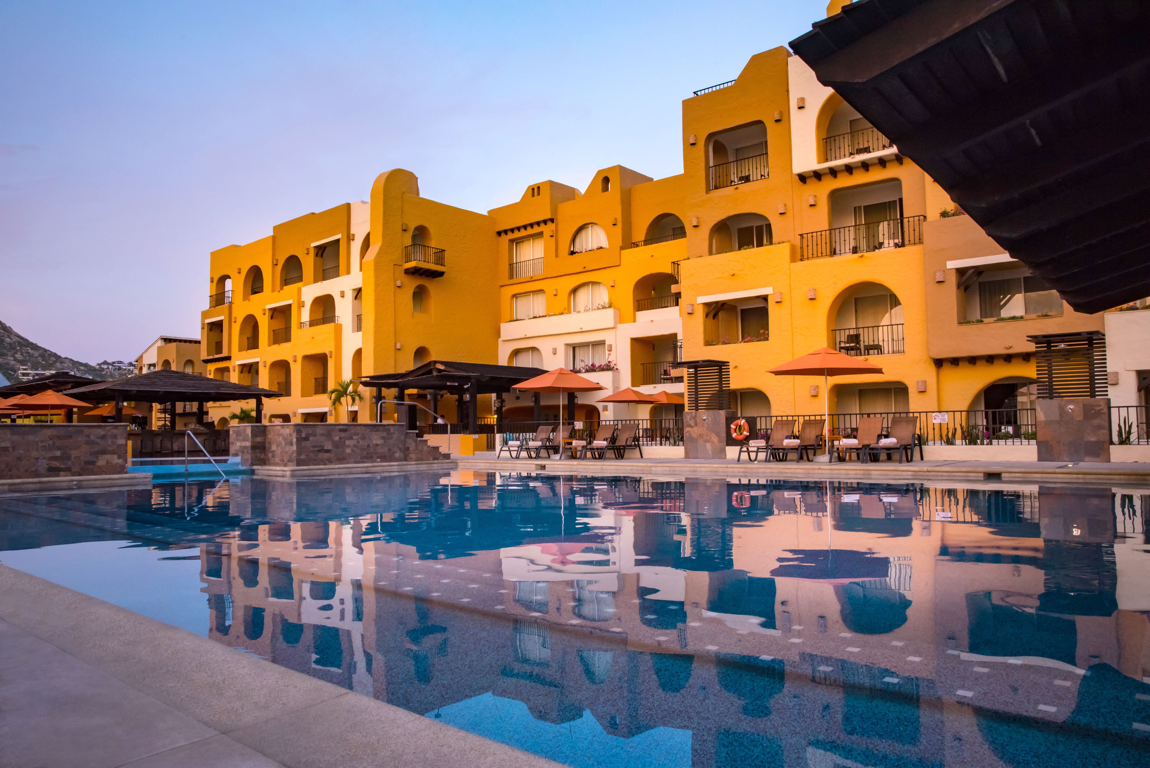 Un hôtel doté d’une piscine, d’un espace extérieur aménagé et de bâtiments aux façades jaunes.