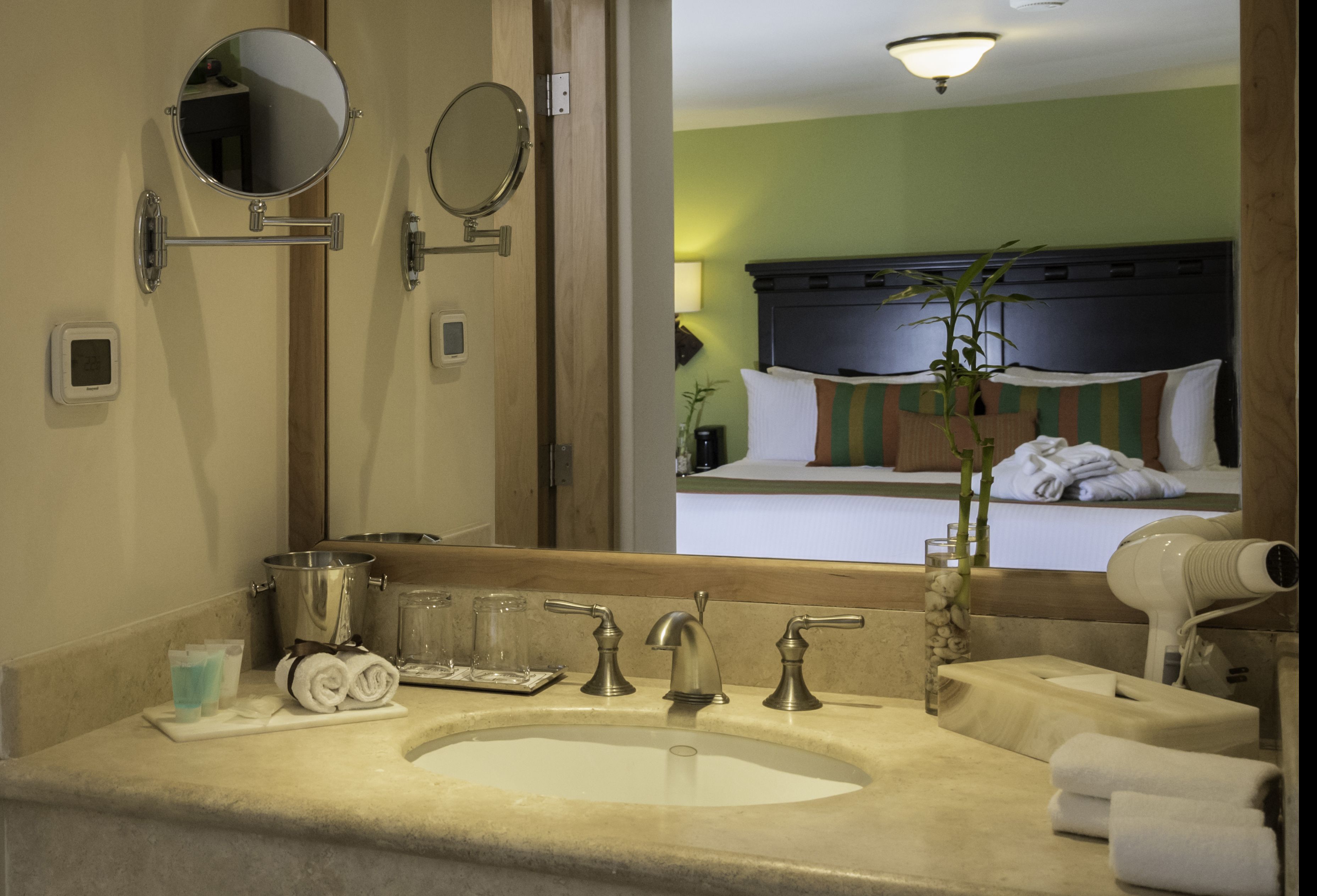 A hotel bathroom with a large sink, two mirrors, a hairdryer, and towels.