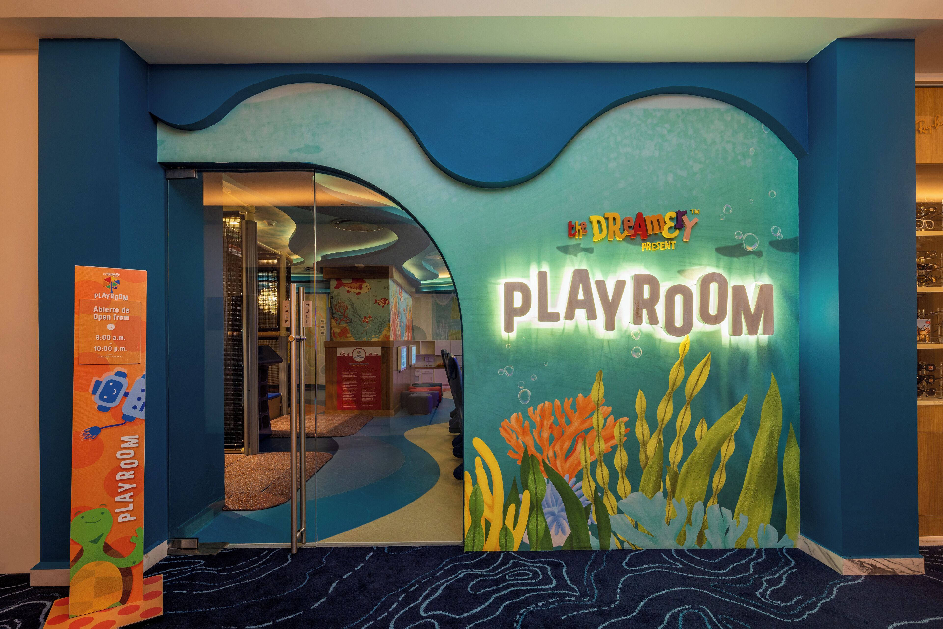 Un salón de juegos con temática acuática en azul y verde, que muestra un cartel que dice "The Dreamy Playroom".