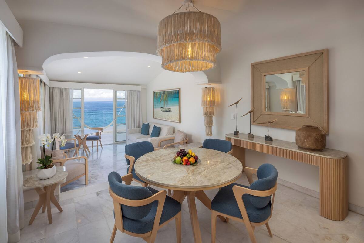 A modern dining area with a round marble table, blue upholstered chairs, and a hanging light fixture.