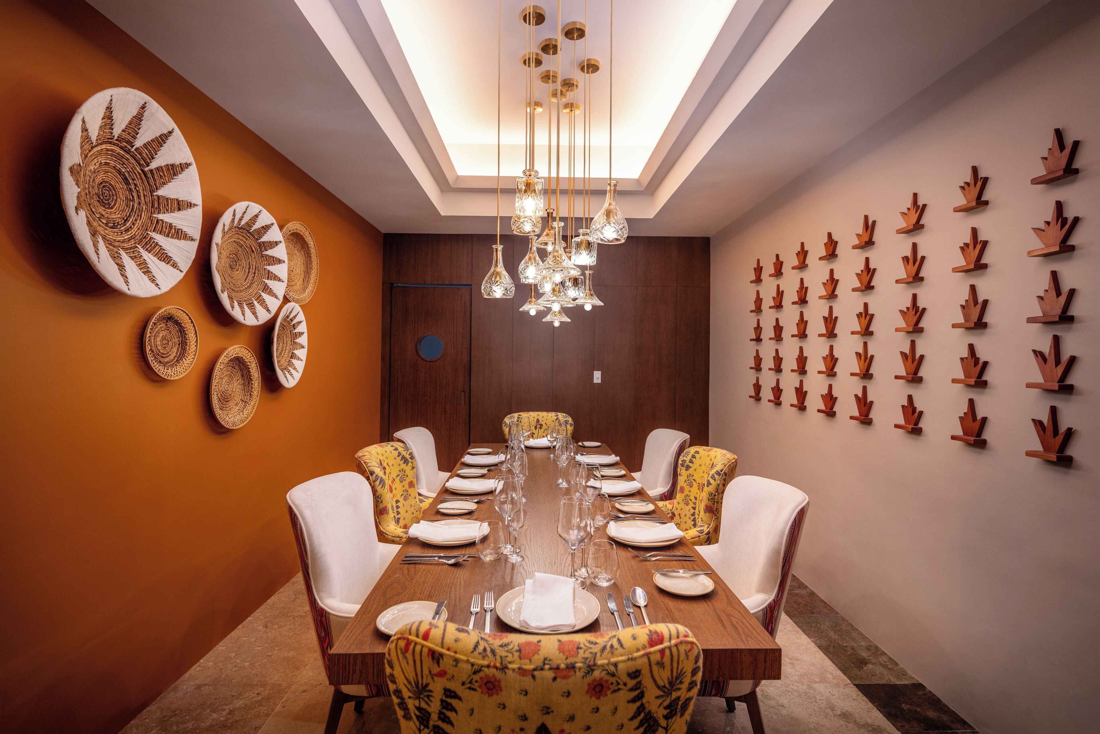 A dining room with a long table set for a meal, surrounded by chairs with floral upholstery.