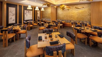 Un restaurante con varias mesas y cabinas, paneles de madera y lámparas colgantes.