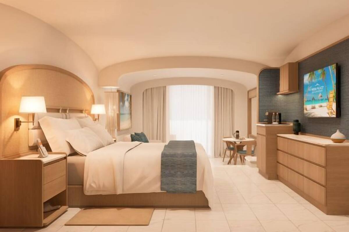 A hotel room with a bed, bedside tables, a desk, a chair, and a large window.