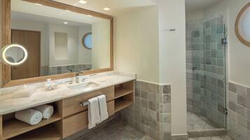 A modern bathroom with a large mirror, two sinks, a shower enclosure, and a wooden vanity.
