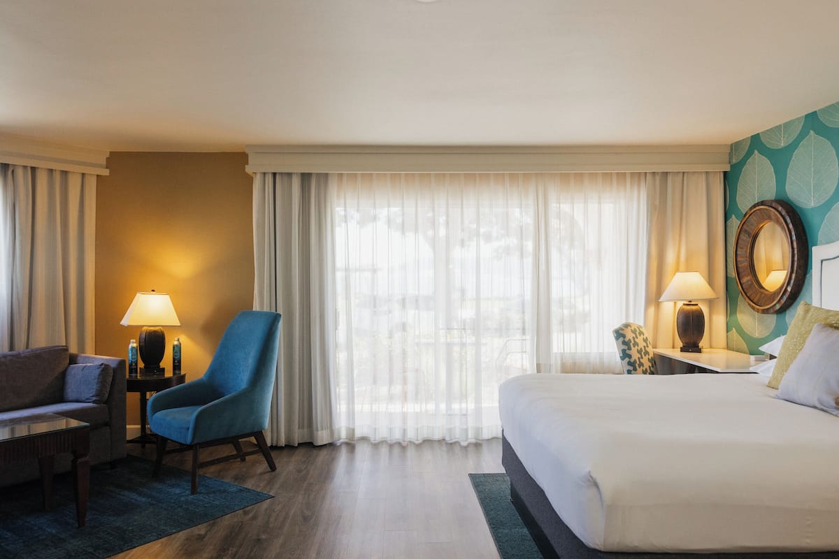 Une chambre d’hôtel avec un lit, une chaise, un bureau et une lampe.