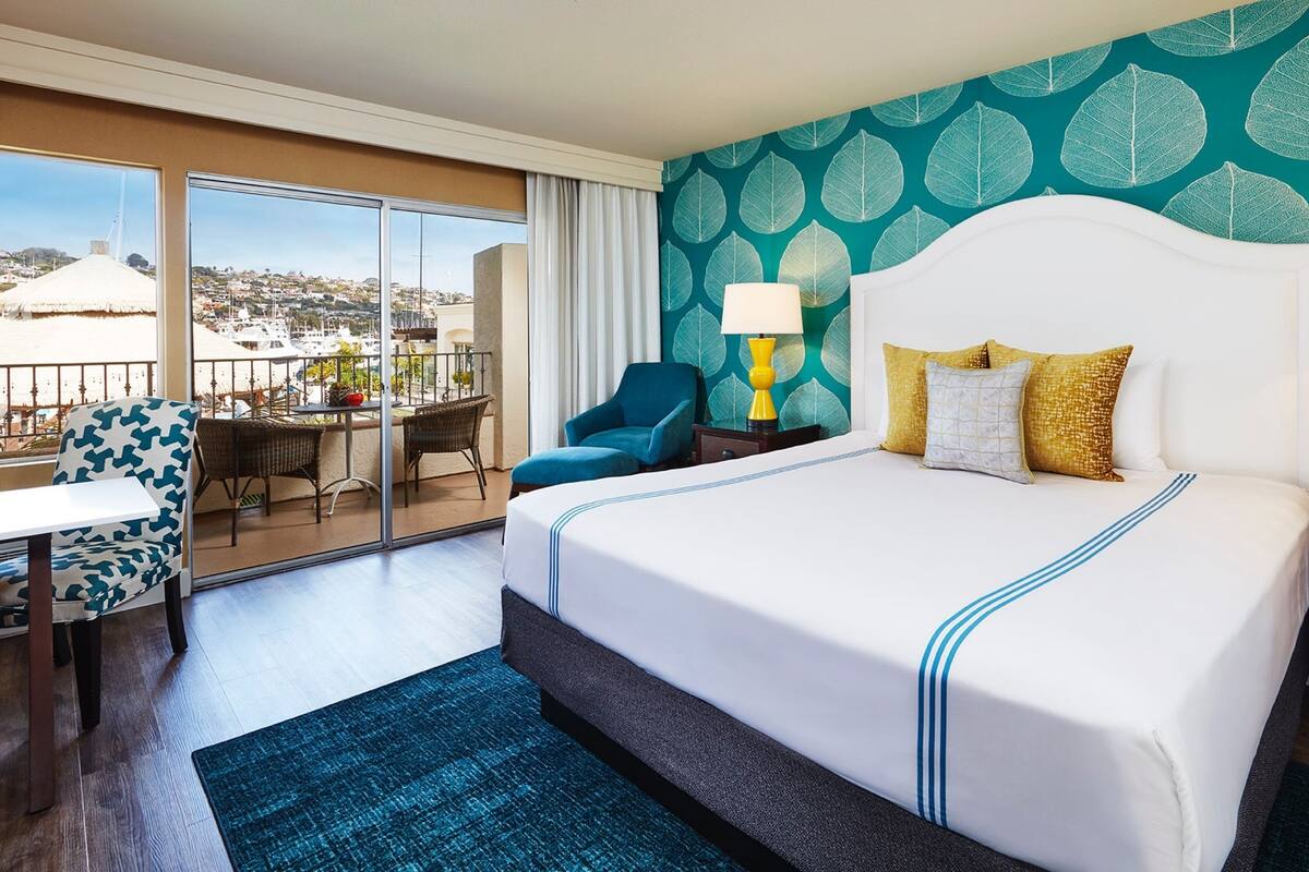 Une chambre d’hôtel avec un grand lit, un balcon avec vue, une chaise et une table.