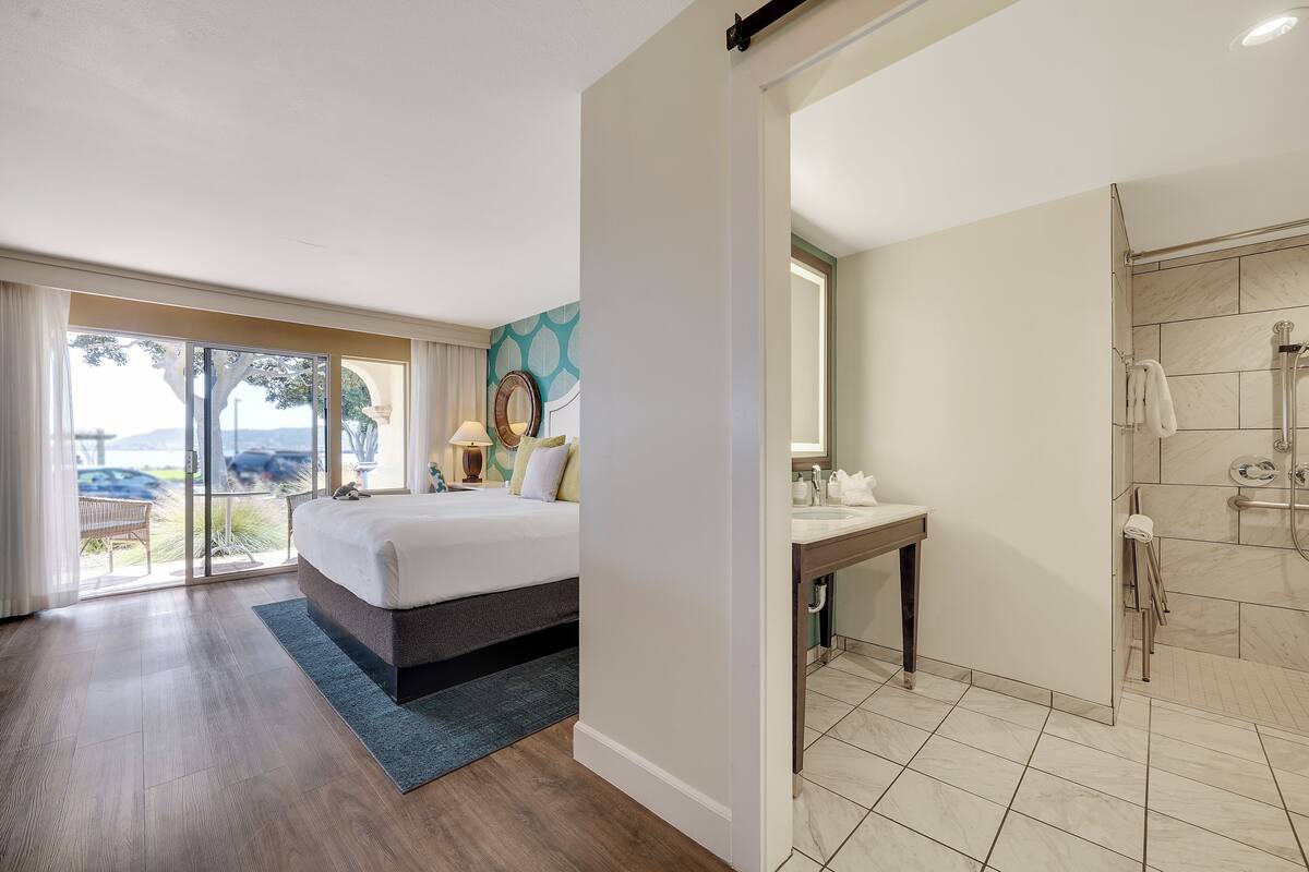 Une chambre d’hôtel comprenant un lit, un bureau, une salle de bain avec douche et une vue sur l’extérieur.