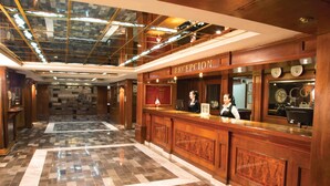 A reception area with a marble floor, wooden reception desk, and a glass ceiling. - Country Plaza (Zapopan)