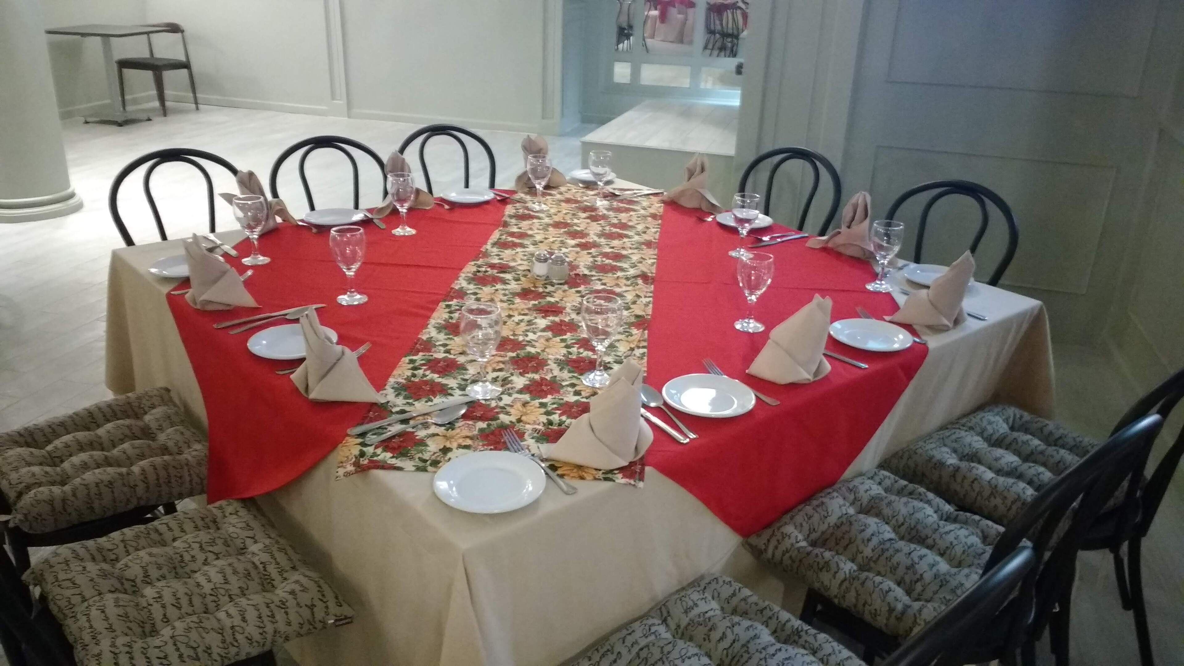 A dining table set for a meal with red tablecloths, white plates, and silverware.