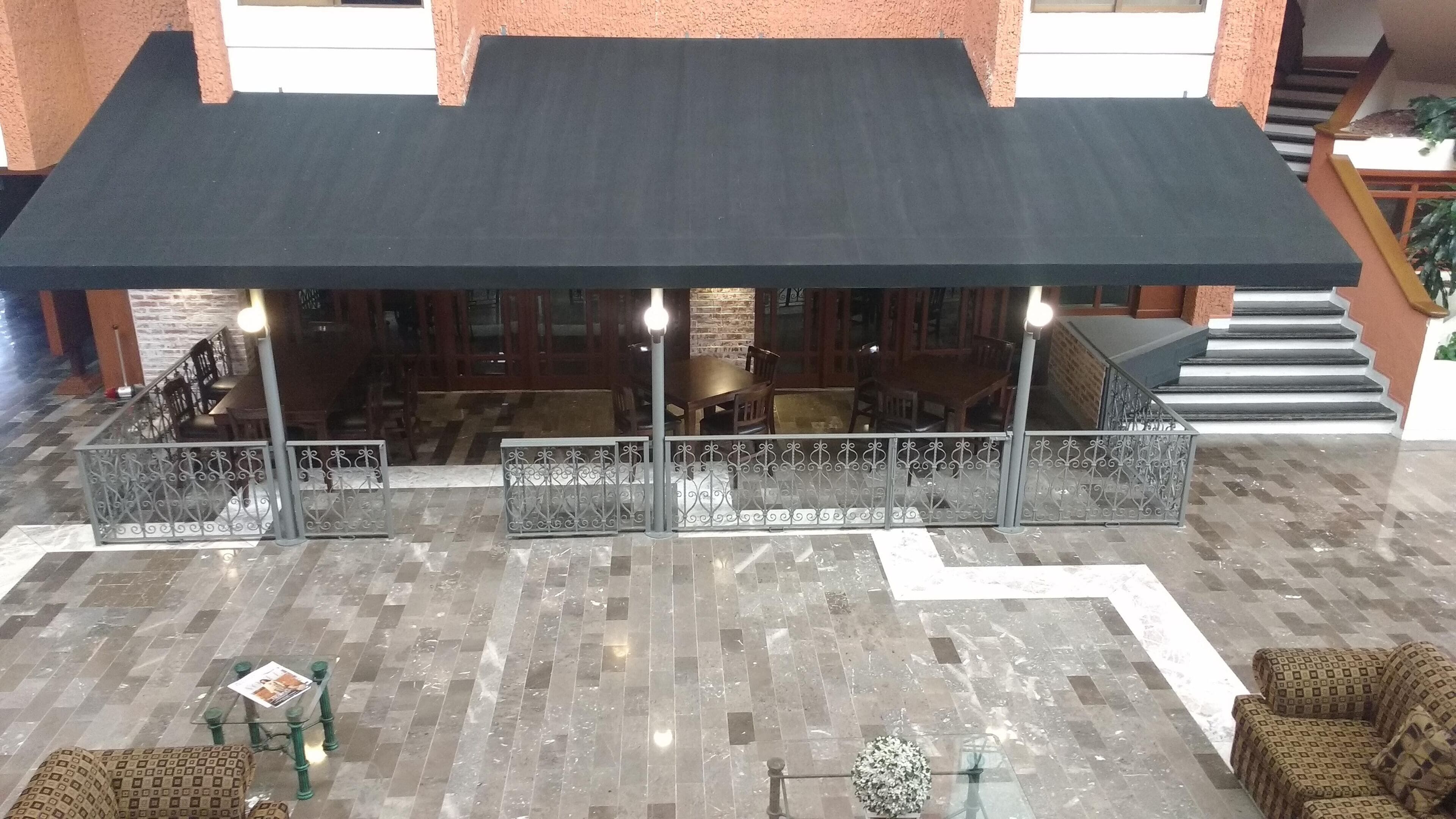 A spacious indoor area with a covered seating area, a staircase, and a patterned floor.