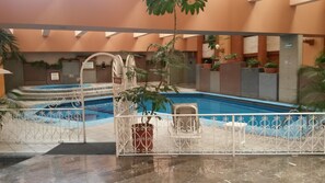 An indoor swimming pool with a marble floor, surrounded by a white metal fence. - Country Plaza (Zapopan)