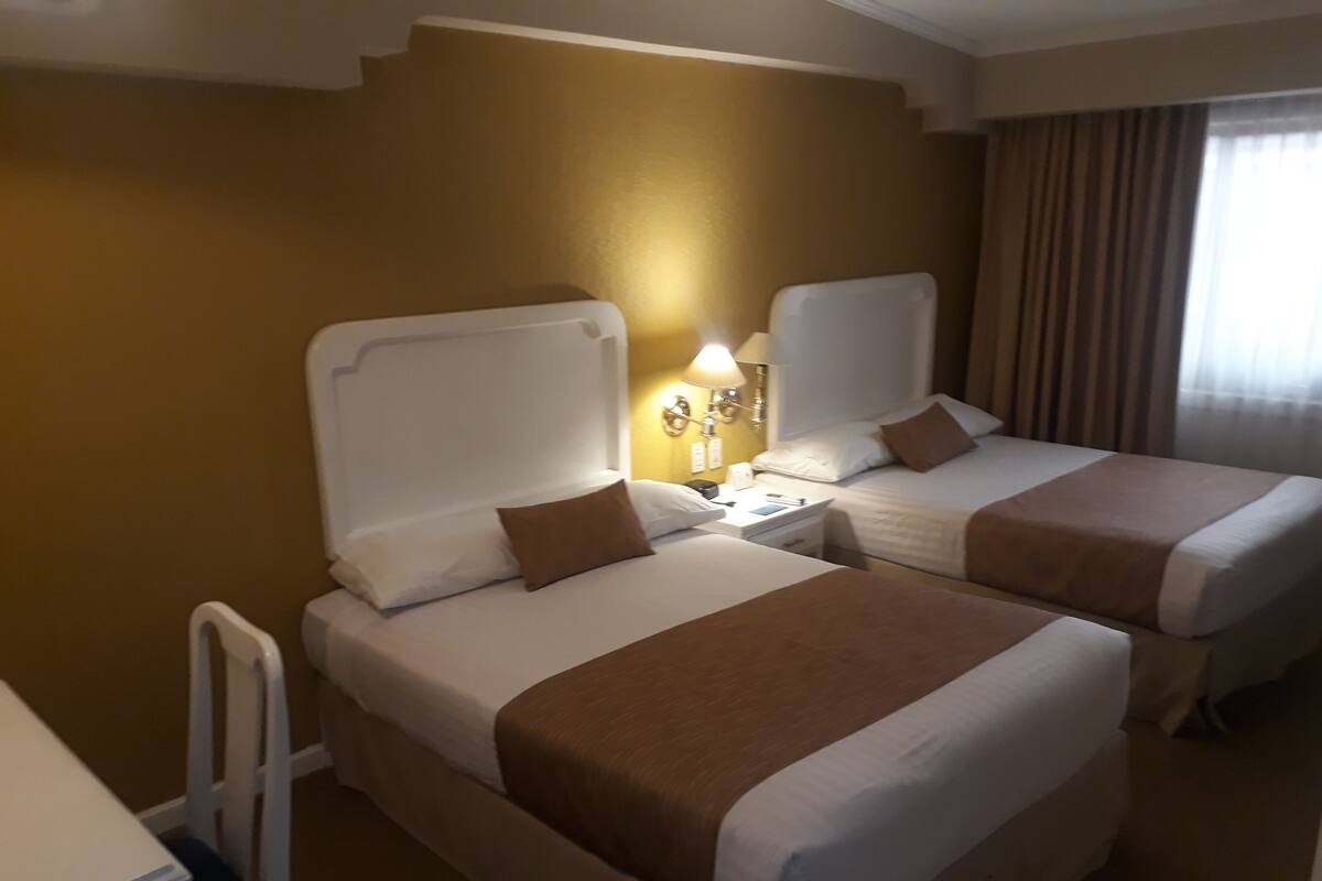 A hotel room with two beds, a desk, and a chair.